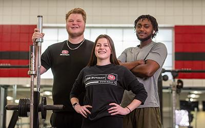 Three students posing in gym